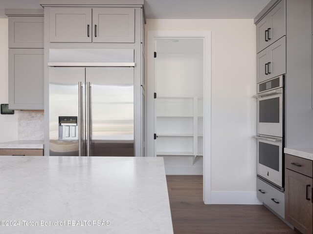 kitchen featuring appliances with stainless steel finishes, gray cabinetry, and dark hardwood / wood-style floors