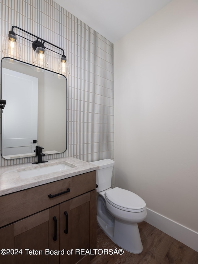 bathroom featuring tile walls, vanity, wood-type flooring, and toilet