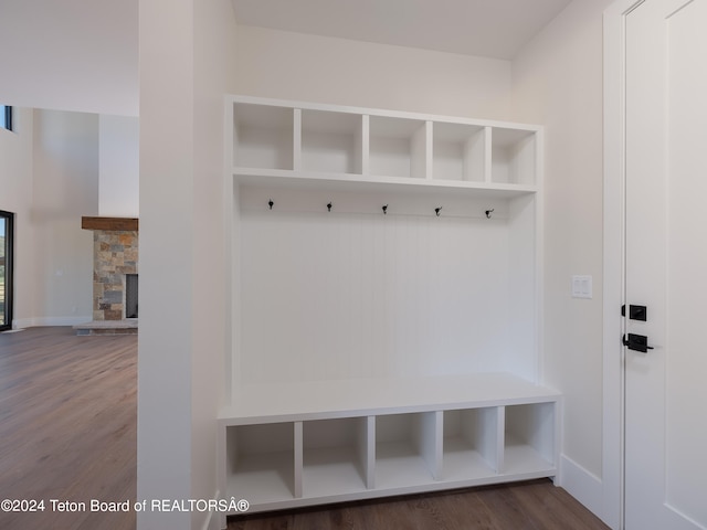 mudroom with dark wood-type flooring and a stone fireplace