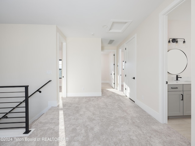 hall with light colored carpet and sink