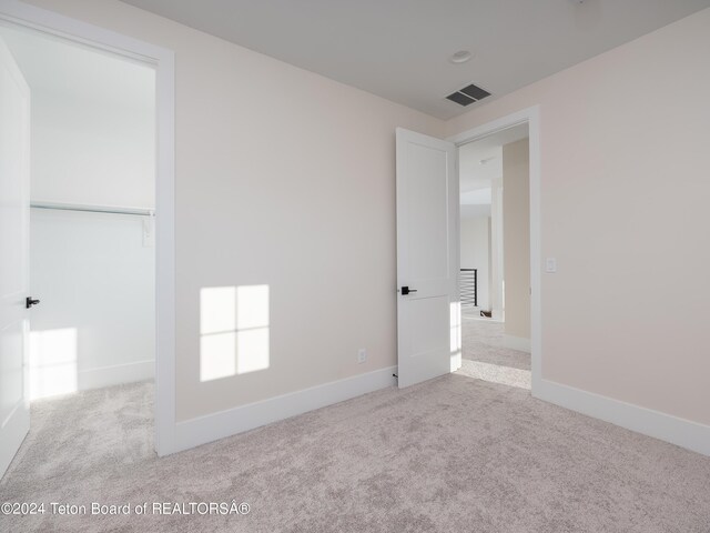 unfurnished bedroom featuring light colored carpet and a closet