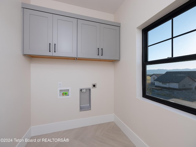 clothes washing area with electric dryer hookup, washer hookup, a mountain view, cabinets, and light parquet flooring