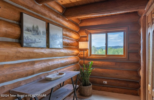 sitting room with wood-type flooring, beam ceiling, wooden ceiling, and log walls