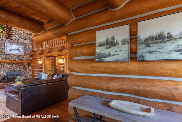 living room featuring wood ceiling, beam ceiling, a stone fireplace, rustic walls, and hardwood / wood-style floors