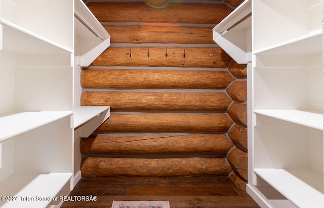 stairs with hardwood / wood-style floors and log walls