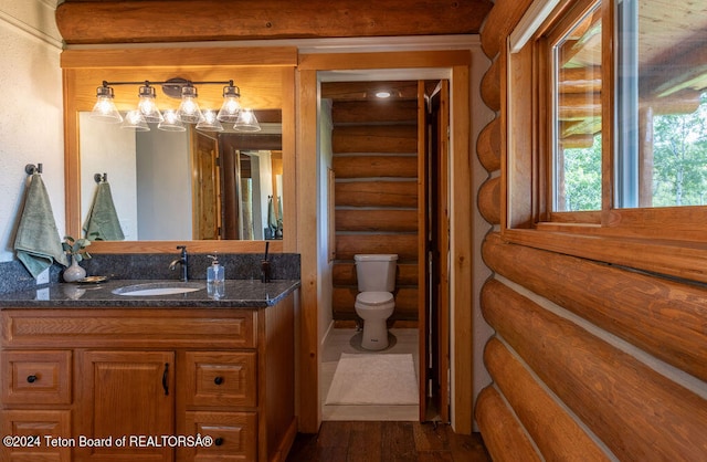 bathroom featuring log walls, hardwood / wood-style floors, vanity, and toilet