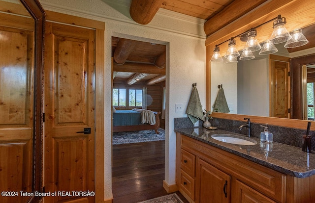 bathroom featuring beamed ceiling, plenty of natural light, vanity, and wood-type flooring