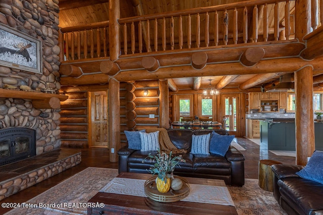 living room featuring a stone fireplace, an inviting chandelier, hardwood / wood-style floors, and rustic walls