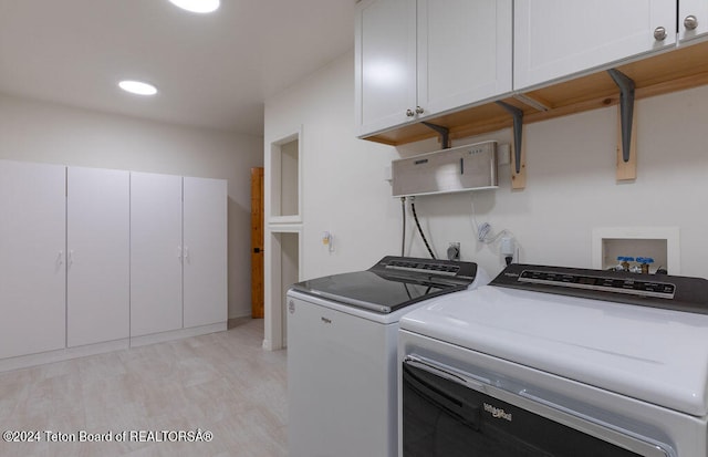 laundry room with separate washer and dryer, cabinets, and light wood-type flooring