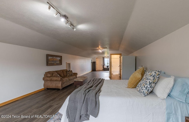 bedroom with track lighting, a textured ceiling, vaulted ceiling, and dark hardwood / wood-style flooring