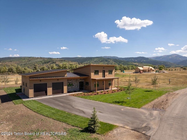 view of front of property featuring a mountain view, a garage, a front yard, and a porch