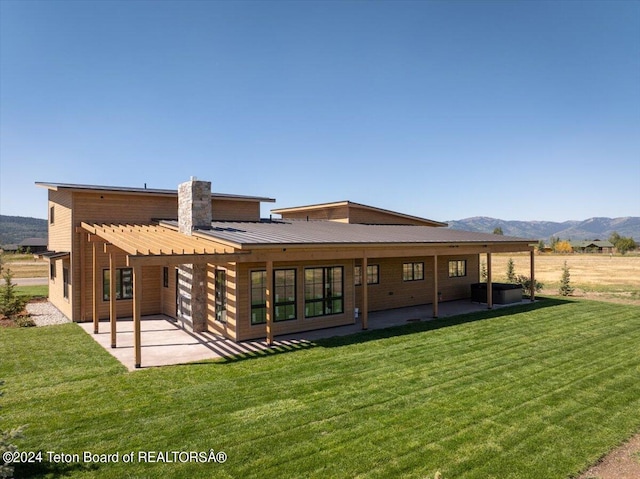 back of house featuring a mountain view, a yard, and a patio area