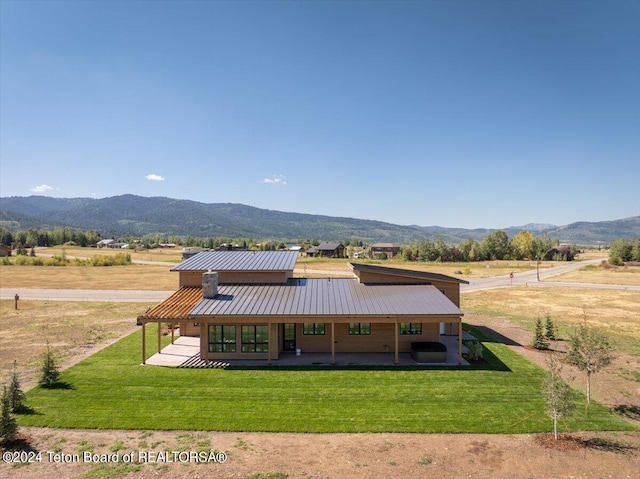 back of property featuring a lawn, a mountain view, and a rural view