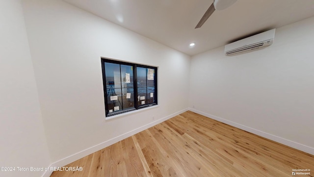 empty room with hardwood / wood-style floors, ceiling fan, and an AC wall unit