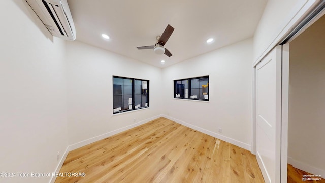 unfurnished bedroom with ceiling fan, a closet, wood-type flooring, and a wall mounted AC