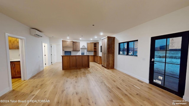 kitchen featuring a wall mounted air conditioner, a center island, and light wood-type flooring