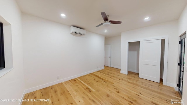 unfurnished bedroom with an AC wall unit, ceiling fan, a closet, and light hardwood / wood-style floors