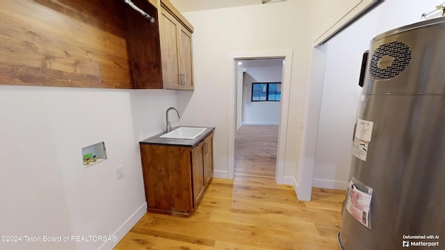 hallway with electric water heater, sink, and light hardwood / wood-style floors