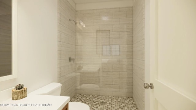 bathroom featuring vanity, toilet, and tiled shower