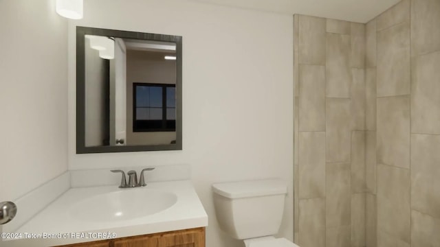 bathroom featuring tiled shower, vanity, and toilet