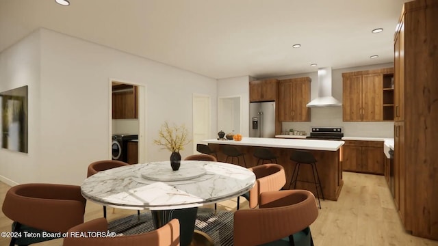 kitchen featuring electric range, wall chimney range hood, a kitchen breakfast bar, stainless steel refrigerator with ice dispenser, and light hardwood / wood-style floors