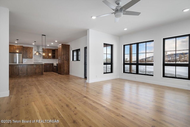 unfurnished living room with ceiling fan and light hardwood / wood-style flooring