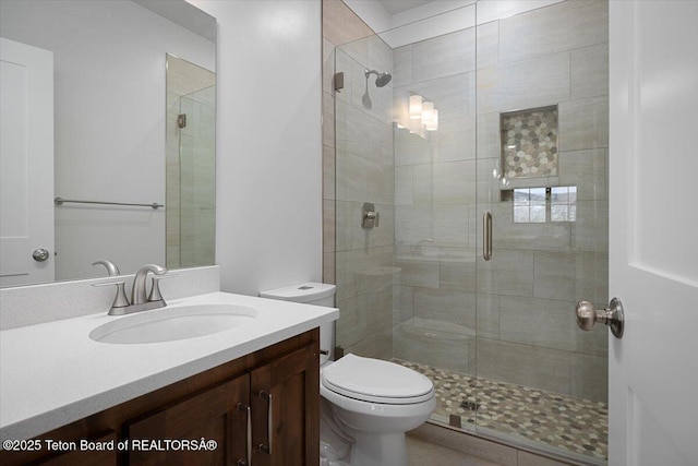 bathroom with vanity, toilet, and a shower with shower door