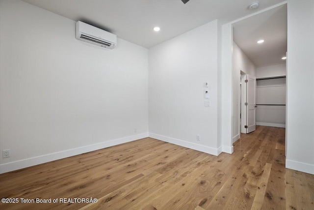 unfurnished room featuring a wall mounted air conditioner and light hardwood / wood-style floors