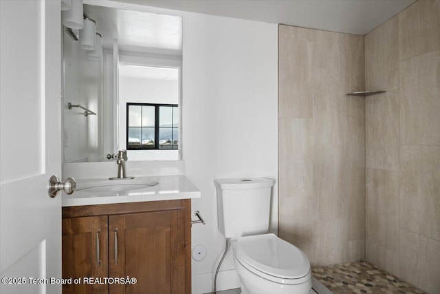 bathroom with vanity, toilet, and a tile shower