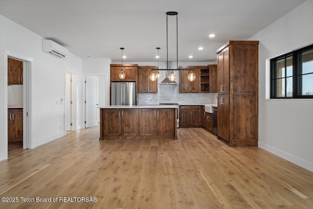 kitchen with a kitchen island, appliances with stainless steel finishes, a wall mounted air conditioner, hanging light fixtures, and wall chimney range hood