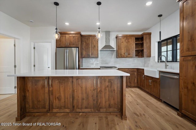 kitchen featuring pendant lighting, sink, backsplash, stainless steel appliances, and wall chimney exhaust hood