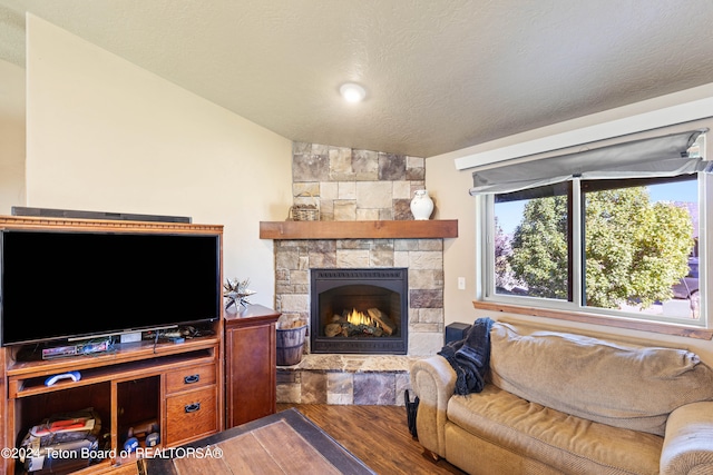 living room featuring a textured ceiling, lofted ceiling, a fireplace, and hardwood / wood-style flooring