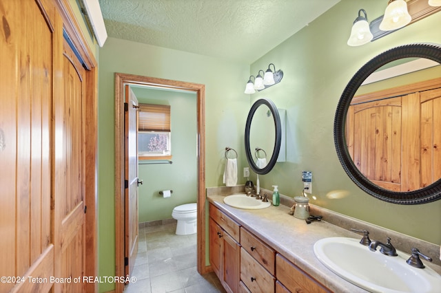 bathroom featuring a textured ceiling, vanity, toilet, and tile patterned floors