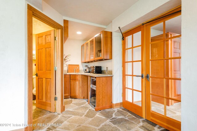 kitchen with a sink, french doors, brown cabinetry, and light countertops