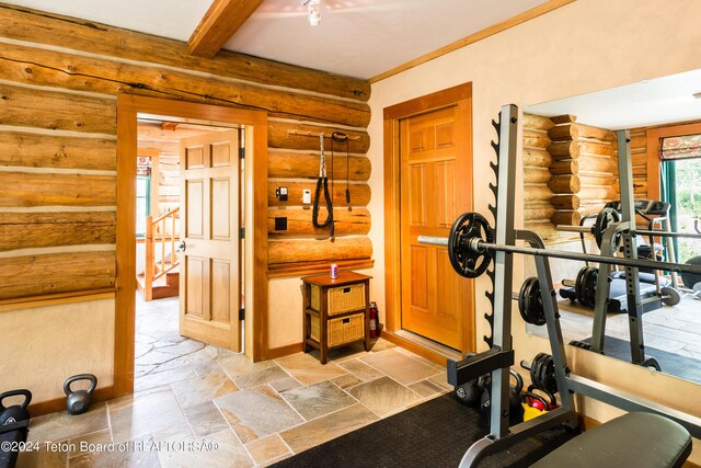 workout room featuring stone tile floors, log walls, and baseboards