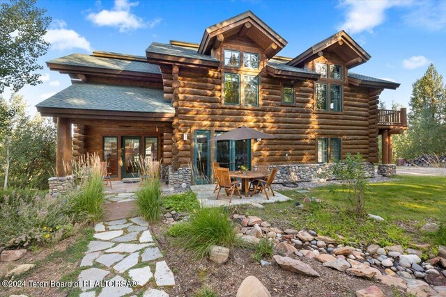 rear view of property featuring a patio and log siding