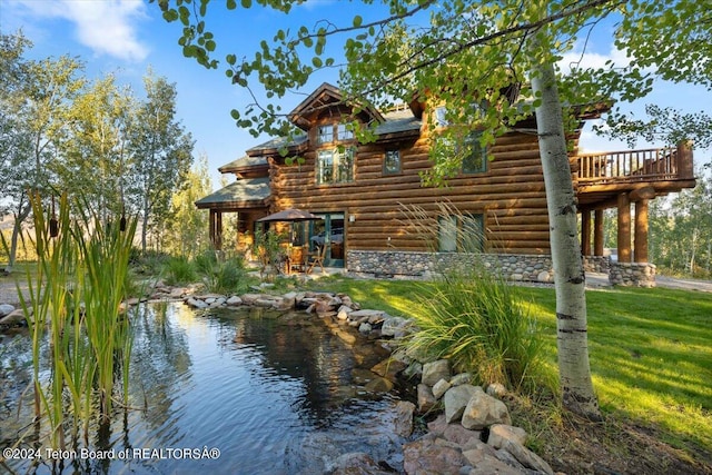 view of side of property featuring a yard, stone siding, and log exterior