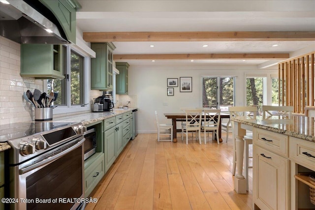 3705 W Mccollister Dr, Teton Village, WY 83025 - kitchen featuring green cabinets, beamed ceiling, light wood-style flooring, appliances with stainless steel finishes, and wall chimney exhaust hood