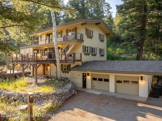 3705 W Mccollister Dr, Teton Village, WY 83025 - view of front of home featuring a balcony, a shingled roof, dirt driveway, and a garage