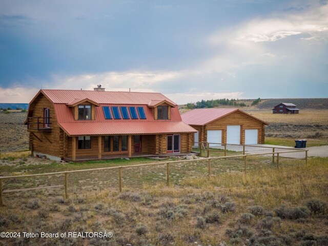 cabin featuring an outdoor structure, a garage, and a rural view