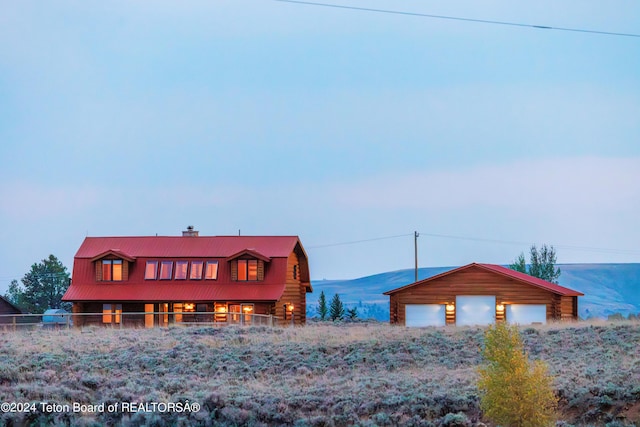 view of front of house with a chimney, an outdoor structure, a garage, log exterior, and a mountain view