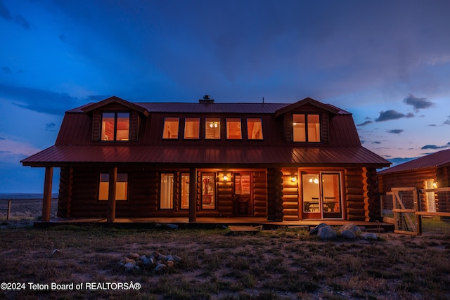 back house at dusk featuring a lawn