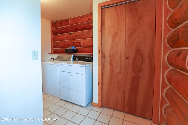 washroom featuring washing machine and clothes dryer, light tile patterned floors, and a textured ceiling