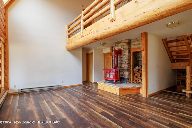 unfurnished living room with a baseboard heating unit, dark wood-type flooring, and a wood stove