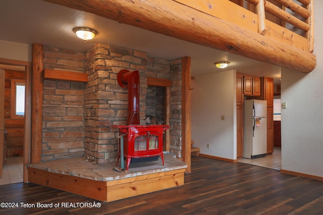 details with a wood stove, wood finished floors, baseboards, and freestanding refrigerator