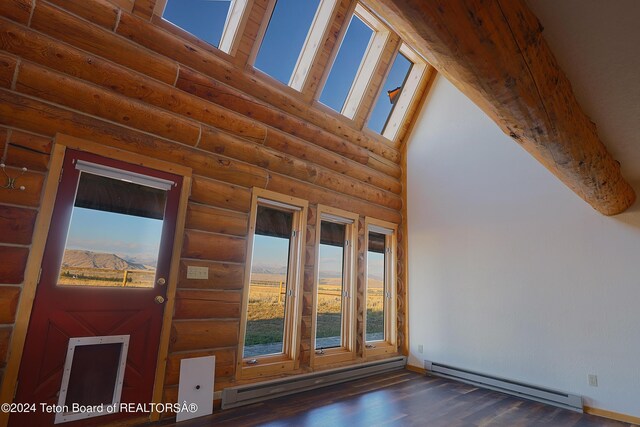 interior space with dark wood-type flooring, a baseboard radiator, rustic walls, and a towering ceiling