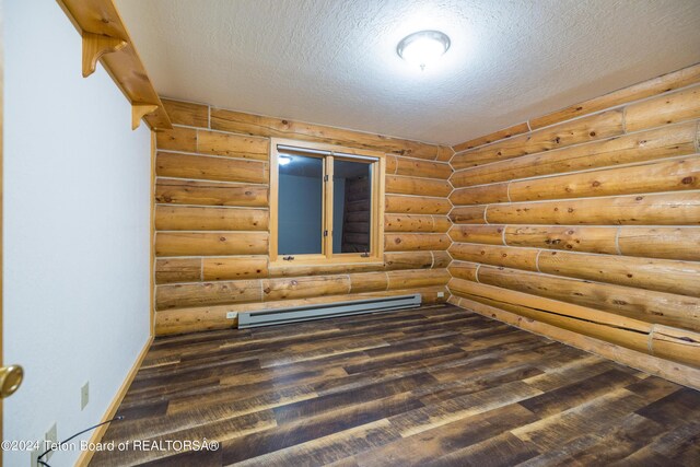 spare room with a textured ceiling, dark wood-type flooring, log walls, and a baseboard radiator