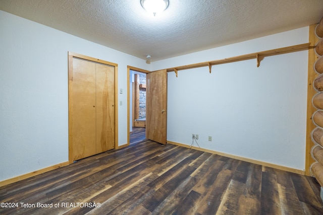 unfurnished bedroom featuring a closet, a textured ceiling, baseboards, and dark wood-style flooring