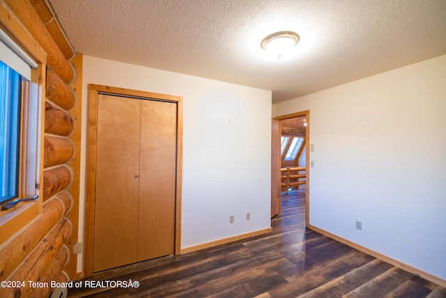 unfurnished bedroom featuring dark wood-type flooring, a textured ceiling, and a closet