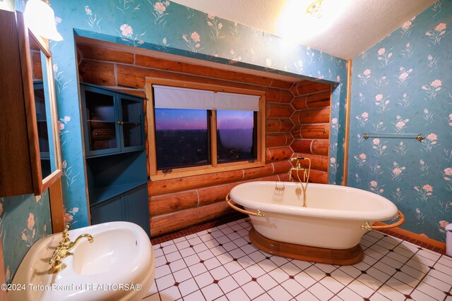 bathroom featuring log walls, tile patterned floors, sink, a bath, and a textured ceiling